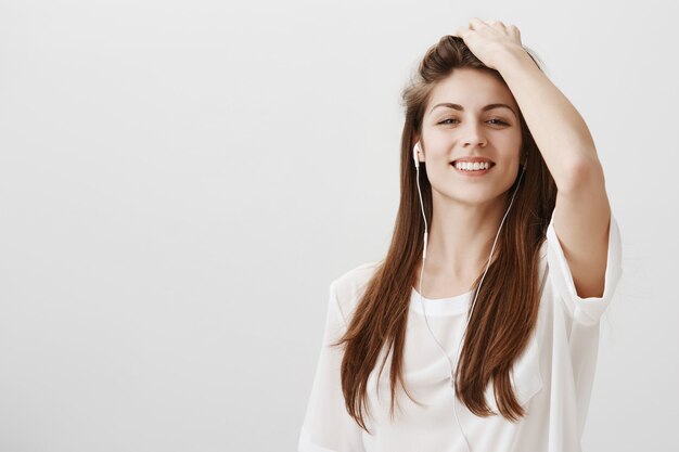 Smiling happy woman enjoying listening to music in earphones