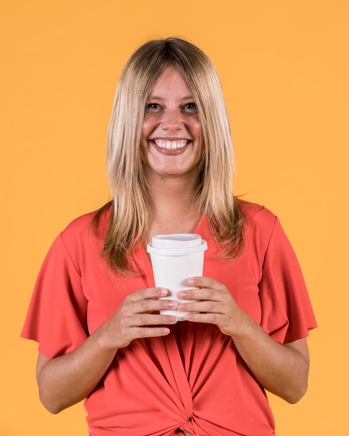 Smiling happy woman holding disposable coffee cup