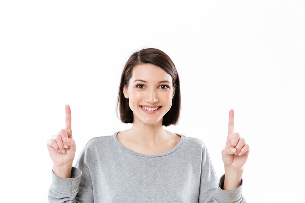 Smiling happy woman pointing two fingers up at copy space