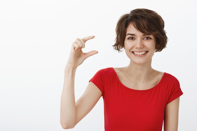 Smiling happy woman showing something small, little thing