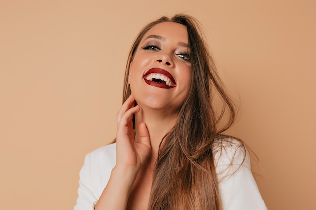 Smiling happy woman with bright make-up looking at camera while touching her cheek