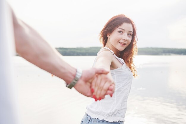 A smiling happy woman with a playful expression and a hand with her husband.