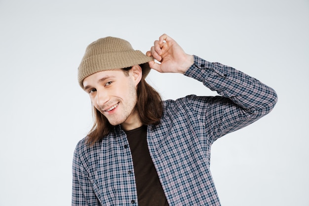 Smiling hipster holding hat and listening