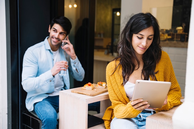 Smiling hispanic female with tablet in cafe