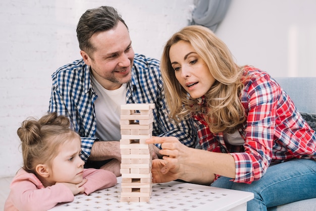 Free photo smiling husband looking their wife while arranging wooden block game tower