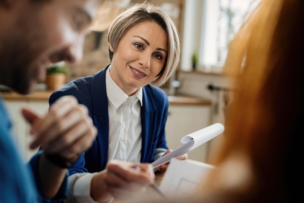 Free photo smiling insurance agent going through paperwork and communicating with her clients during a meeting.