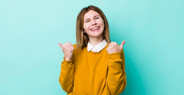 Free photo smiling joyfully and looking happy feeling carefree and positive with both thumbs up