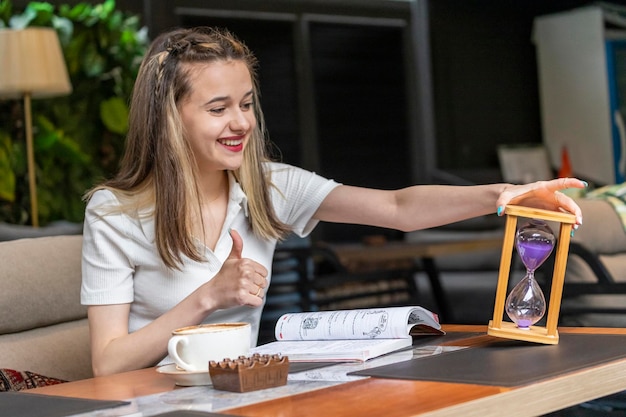 Smiling lady holding hourglass and gesture thumb up