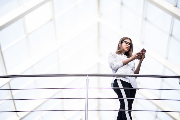 Free photo smiling lady successful business women standing resting and looking through on balcony in modern office centre dressed up in white t-shirt