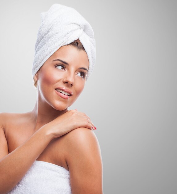 Smiling lady in towel over grey background.