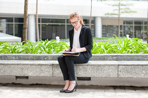 Smiling Lady Working and Sitting on Flowerbed