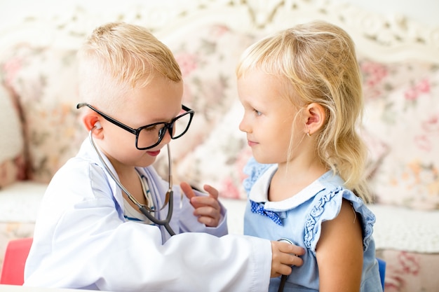 Free photo smiling little boy playing doctor with girlfriend