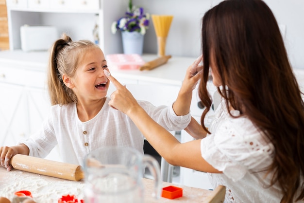 Free photo smiling little girl cooking with her mother