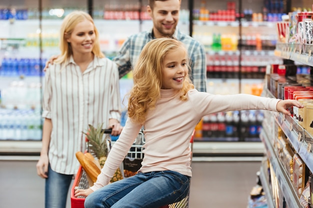 Free Photo smiling little girl sitting on a shopping cart