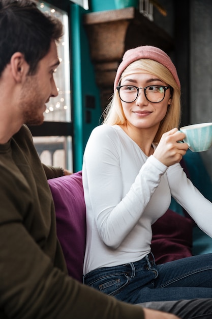 Free photo smiling loving couple sitting in cafe and drinking coffee