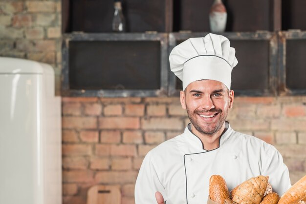 Smiling male baker holding baguettes