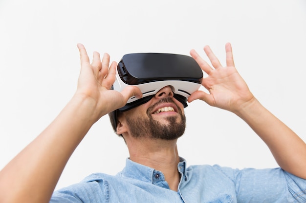 Smiling male user wearing VR glasses, adjusting device