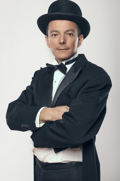 Smiling man in black suit and cylinder hat.