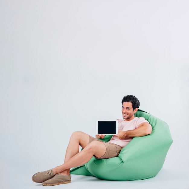 Smiling man on couch presenting tablet