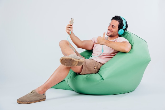 Smiling man on couch taking selfie with smartphone