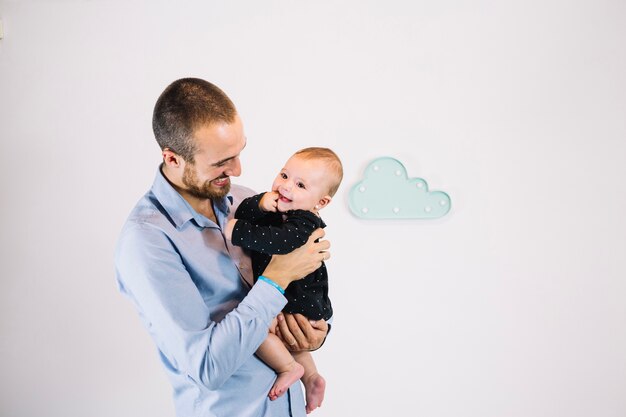 Smiling man holding cheerful baby