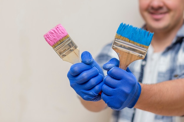 Smiling man holding pink and blue paint brush