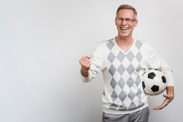 Smiling man holding a soccer ball with copy-space