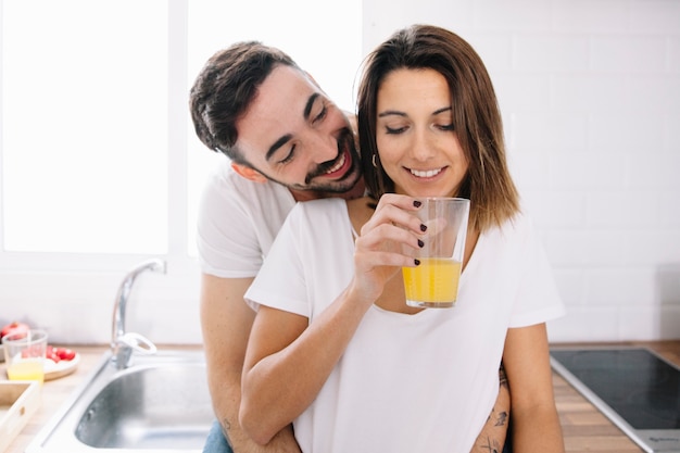 Free photo smiling man hugging woman with juice