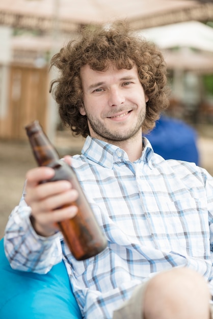 Free photo smiling man offering beer to camera