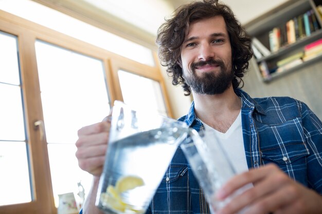 Smiling man pouring lemonade in the glass