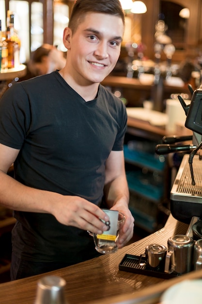 Smiling man putting tea ba into cup