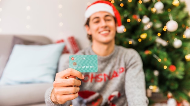 Smiling man in Santa hat holding credit card 