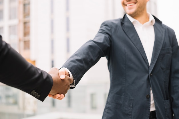 Free photo smiling man shaking hand of colleague