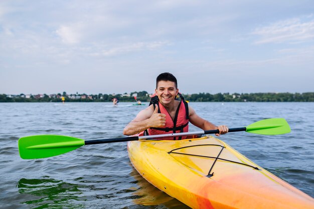 Smiling man showing thumb up sign while kayaking