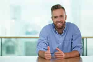 Free photo smiling man sitting at cafe table and gesturing