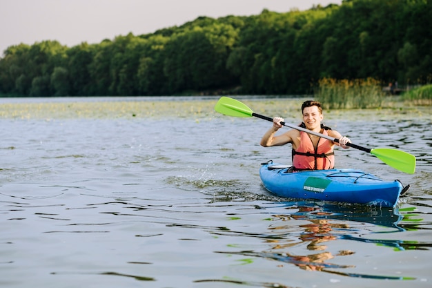 Smiling man splashing water while paddling the kayak on lake