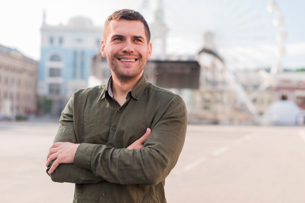 Smiling man standing in amusement park with arm crossed