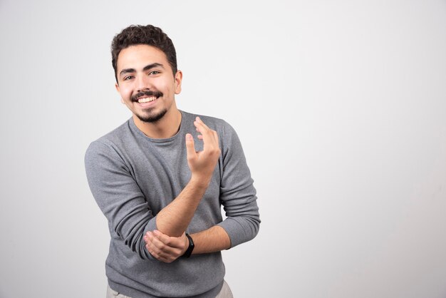 Smiling man standing and posing over a white wall.