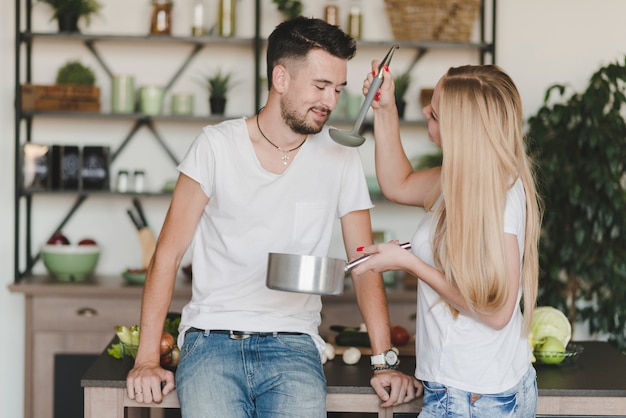 Free Photo smiling man tasting the soup prepared by woman in the kitchen