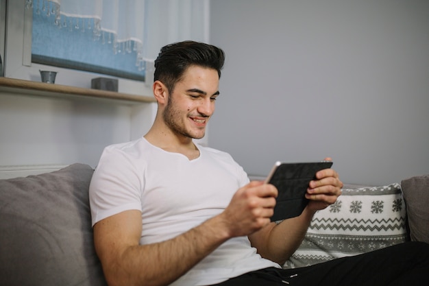 Smiling man using tablet on couch