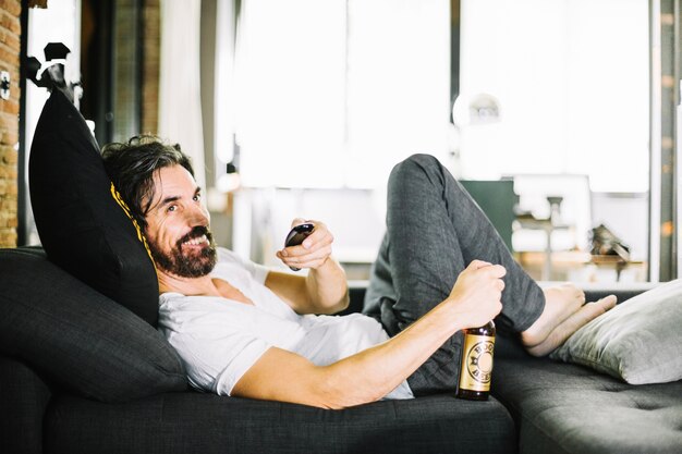 Free photo smiling man with beer enjoying tv