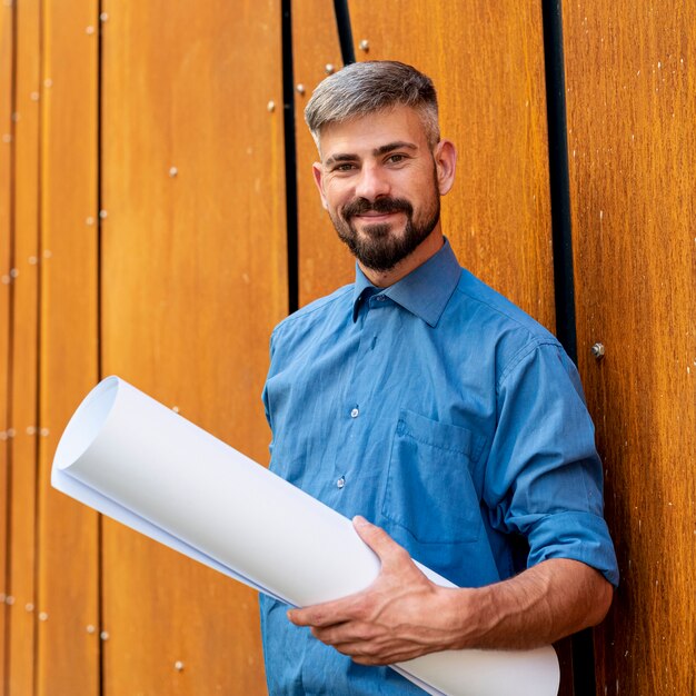 Smiling man with blue shirt and schematics