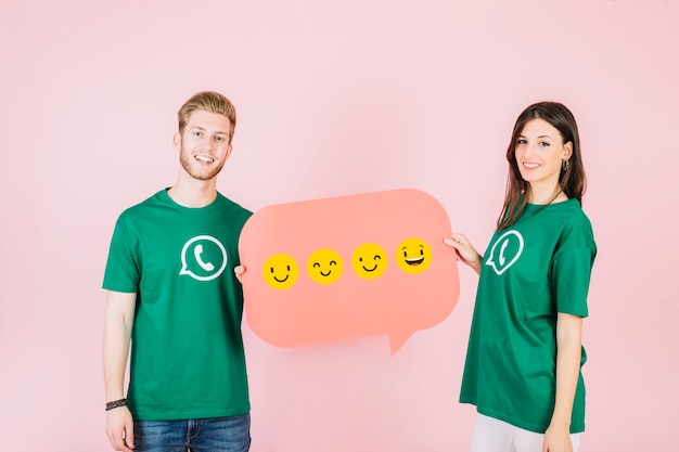 Free photo smiling man and woman holding speech bubble with various type of emoticons