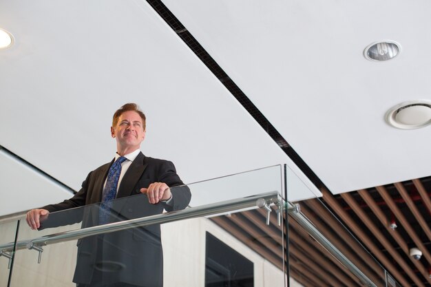 Smiling mature businessman standing in office hall