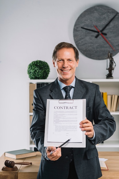 Free photo smiling mature lawyer pointing at signature place on a contract document