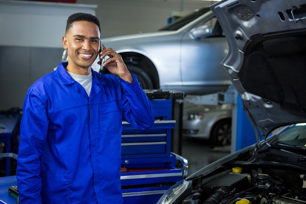 Smiling mechanic talking on a mobile phone