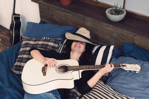 Smiling musician with guitar on bed