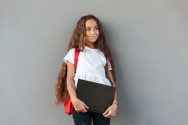 Free Photo smiling mystery brunette schoolgirl with long hair hugging book