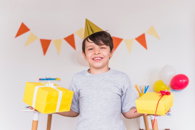 Free Photo smiling portrait of a boy holding birthday presents in his hand