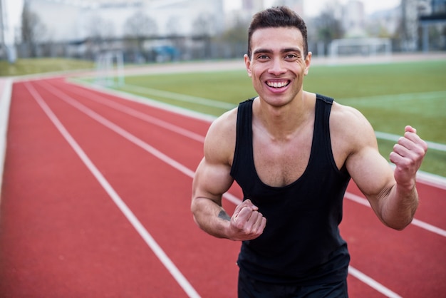 Smiling portrait of a male athlete clenching his fist after winning race